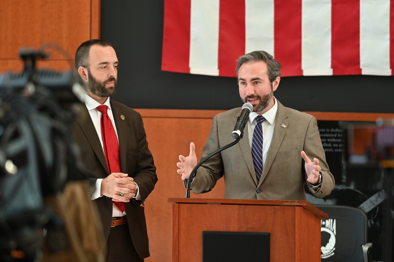 Representatives Thomas and Adam Mathews speaking at an event